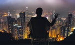 Silhouette of businessman sit on chair and hold a cigar, looking the harbor of Victoria at Hong Kong, Asia.