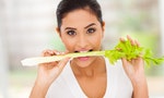portrait of beautiful young woman eating a stick of celery