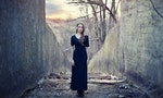 Beautiful lonely girl  in long dress near gloomy tunnel on sunset
