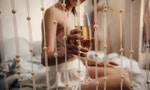 Close-up partial view of young woman holding glass of wine in bedroom — Photo by VitalikRadko