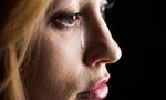 Close-up side view of young woman crying isolated on black — Photo by IgorTishenko