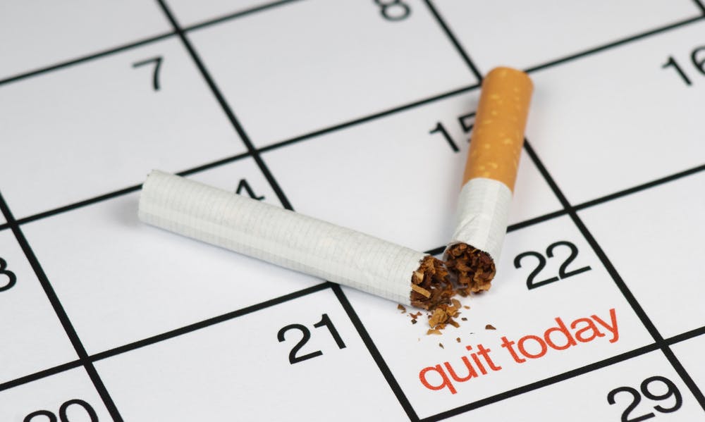 A broken cigarette above a calendar, saying "quit today" — Photo by pedrobento01