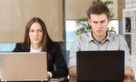 Front view of two angry businesspeople using computers disputing at workplace and looking sideways each other with envy - 圖片