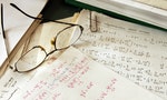 glasses over physics formulas and calculations written on paper