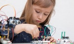 A cute girl constructs metal robot and program it. The boards and microcontrollers are on the table. STEM education inscription. Programming. Mathematics. The science. Technologie. DIY. - 圖片