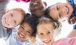 Closeup face of happy multiethnic children embracing each other and smiling at camera. Team of smiling kids embracing together in a circle. Portrait of young boy and pretty girls looking at camera. - 