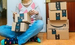 PARIS, FRANCE - JAN 13, 2018: Stack of Amazon Prime packages delivered to a home door woman unboxing one of the small boxes. Amazon is the largest internet based retailer in the United States - 圖片