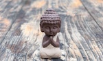 Morning meditation. Little buddha or monk figurine doing yoga exercises