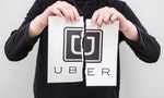 Minsk, Belarus - March 11, 2017: Boy breaks the logo of the world famous social service Uber, printed on paper. Concept. World problem for taxi.