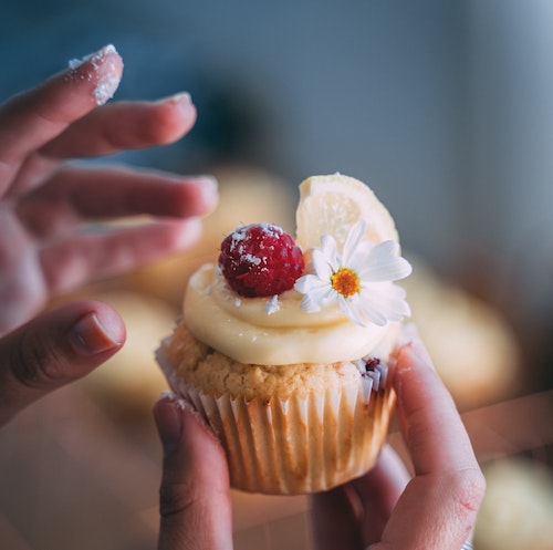 person-holding-cupcake-with-white-icing-