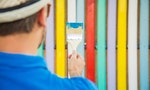 Rear view close up of modern man holding paint brush against colorful wooden fence