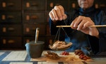 中醫 中藥 Man measuring ingredients in traditional Asian apothecary