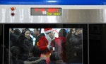 Beijing/China-12/23/2018: A santa gives the ok sign and brings some color and joy to contrast with the tired faces and dark dull Beijing subway coach
