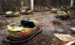 Old broken rusty metal radioactive yellow cars, children's electric cars, abandoned among vegetation, the park of culture and recreation in the city of Pripyat, the Chernobyl disaster, Ukraine.