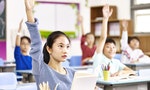 asian elementary school boys raising hands to answer questions during class in classroom.